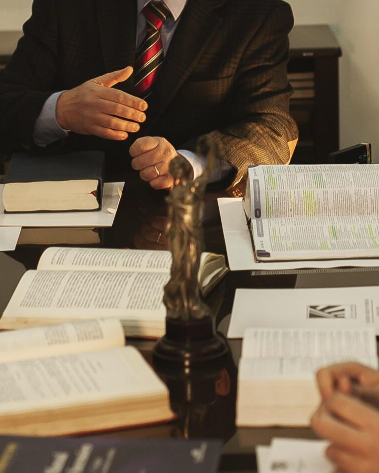 Estátua da Justiça e livros jurídicos na mesa de reuniões do escritório em Alegrete